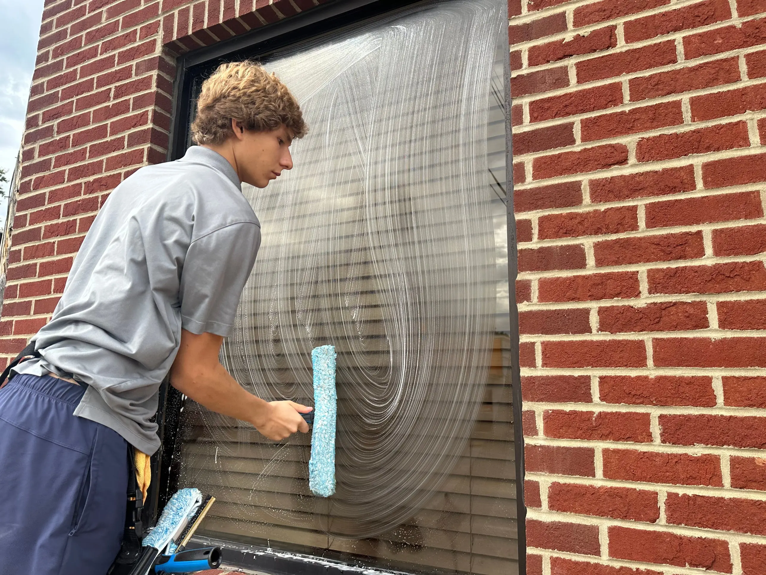 A Clearwater Window Care technician scrubbing a window with a soapy applicator