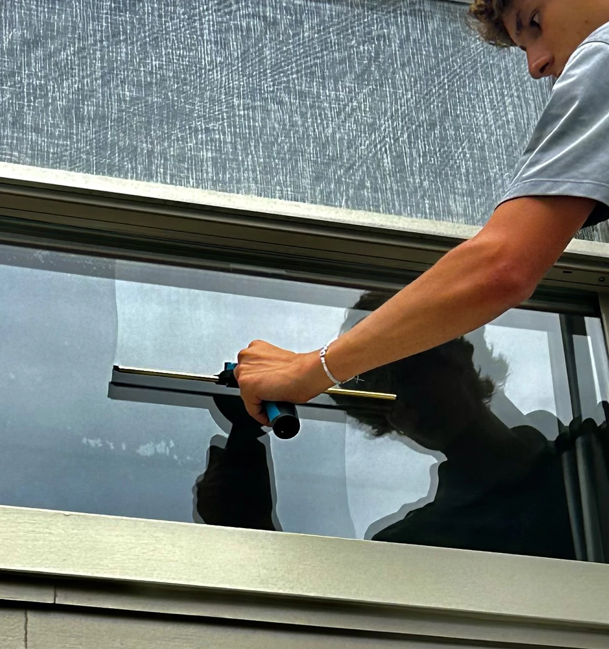 A Clearwater Window Care technician squeegeeing a window from a ladder